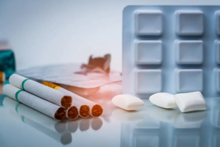 "Four cigarettes beside a blister pack of nicotine gum with three gum pieces placed outside, showing contrast between smoking and quitting aids