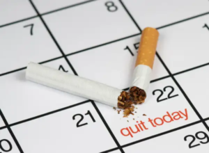 Broken cigarette placed across a calendar page, with tobacco spilling out and “quit today” written in red on the 22nd—symbolizing the urgency and choice to stop smoking.