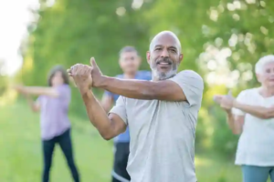 Group of people stretching outdoors on a grassy park lawn with trees in the background—engaging in physical exercise as a symbol of renewed health and vitality after quitting smoking.
