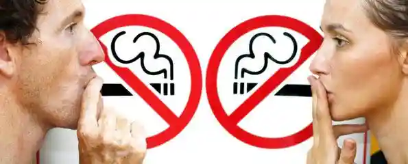 Two “No Smoking” signs with crossed-out cigarette icons inside red circles, placed side by side—emphasizing a smoke-free policy in a shared or public setting.
